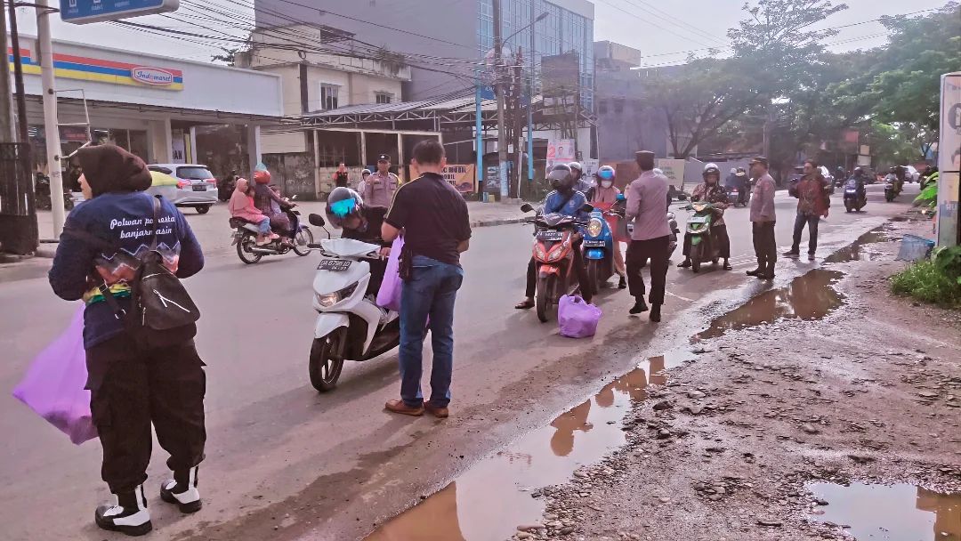 Anggota Polsek Banjarmasin Timur membagikan nasi bungkus kepada pengguna jalan di kawasan Jalan Pangeran Hidayatullah, Keluarahan Banua Anyar, Banjarmasin. Foto: Humas Polsek Banjarmasin Timur