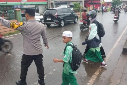 Kanit Samapta Polsek Banjarmasin Selatan, AKP Jumatno memabntu siswa sekolah menyeberang, Rabu (8/1/2025). Foto: Polsek Banjarmasin Selatan