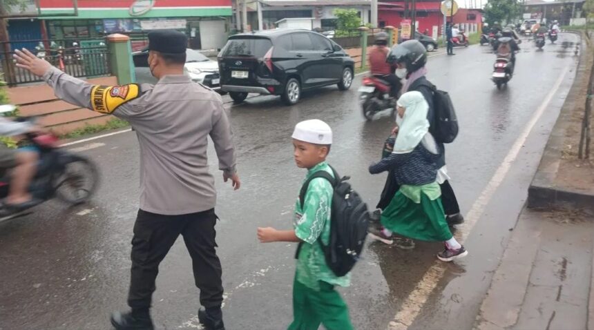 Kanit Samapta Polsek Banjarmasin Selatan, AKP Jumatno memabntu siswa sekolah menyeberang, Rabu (8/1/2025). Foto: Polsek Banjarmasin Selatan