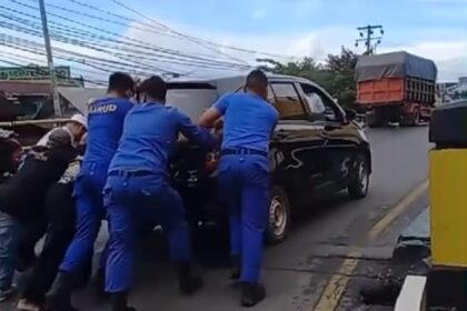 Teks Foto: Personel Sat Polairud Polresta Banjarmasin dan relawan haul membantu mendorong mobil Jemaah yang mogok, Selasa (25/2/2025). Foto: siberdbn.com/Riana